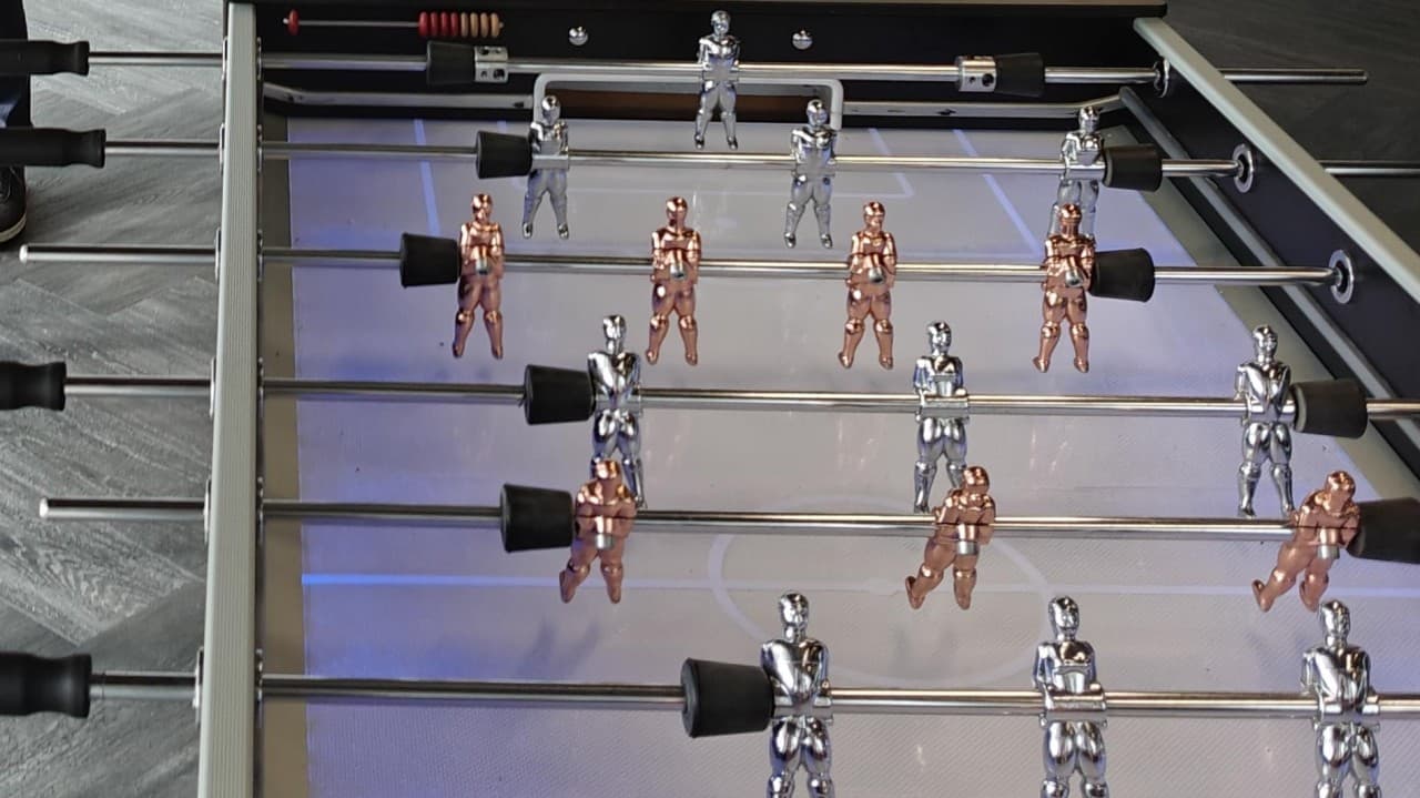 Close-up of a foosball table with silver and copper players