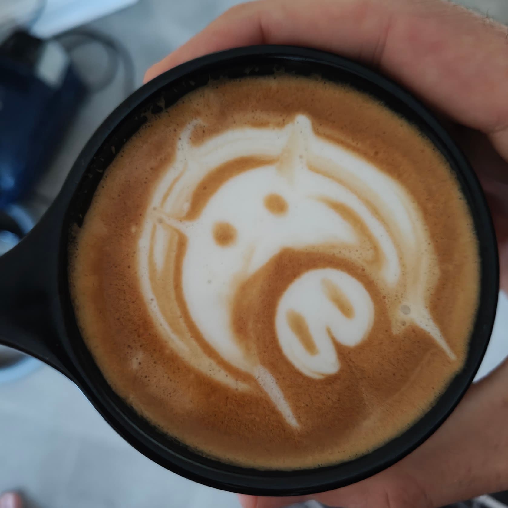 A flat white with milk poured into the shape of a pig's face