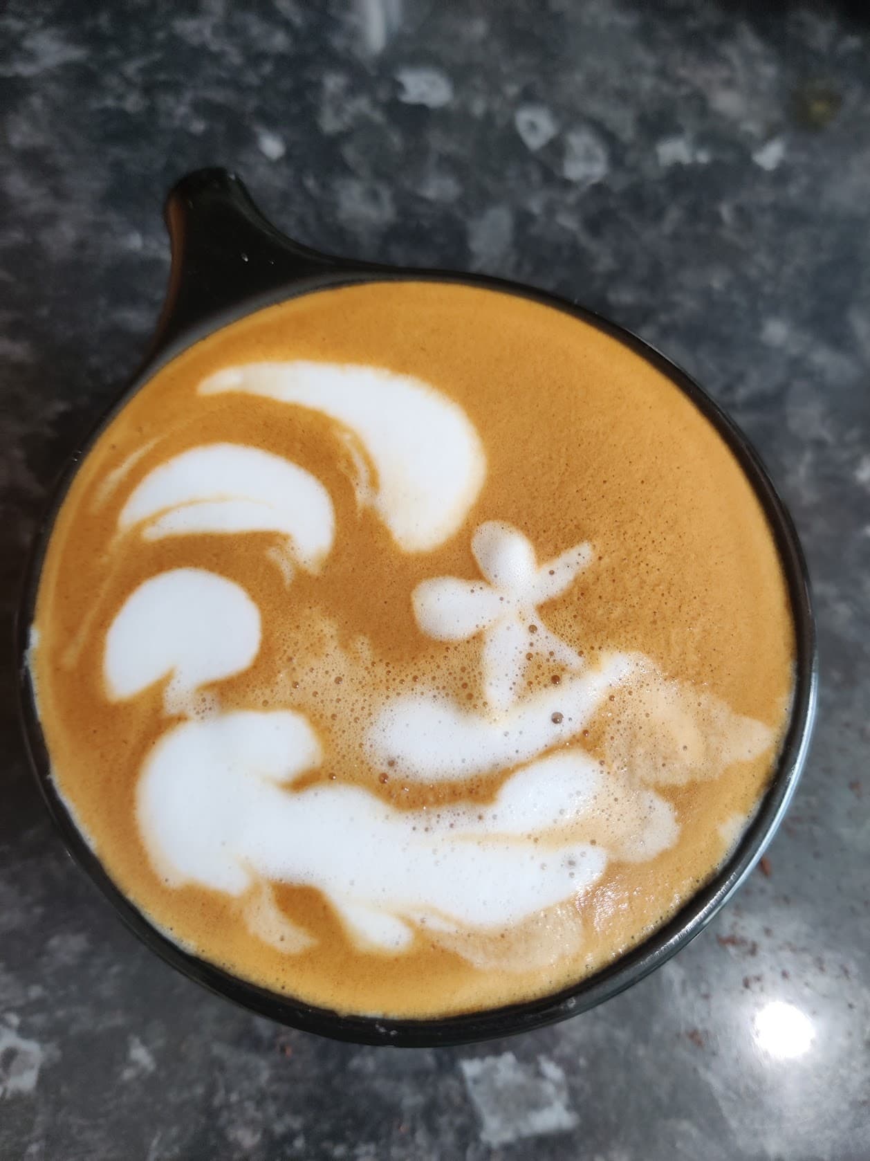 A coffee with milk poured into a big wave and a tiny surfer riding it